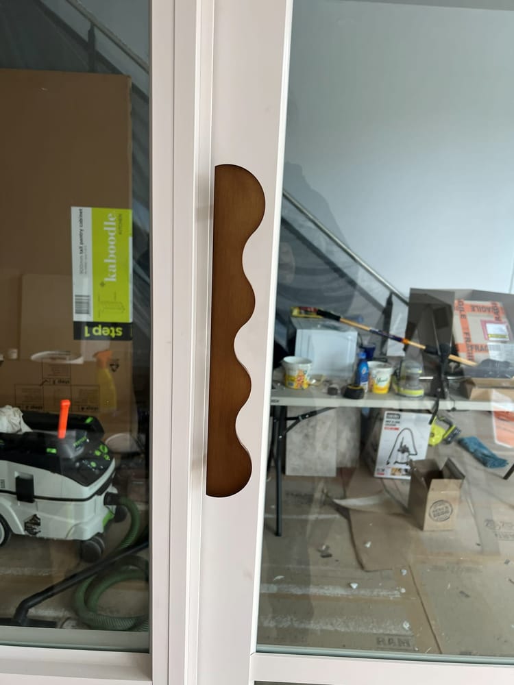 A shaped timber pull handle fitted to a door in a fit-out