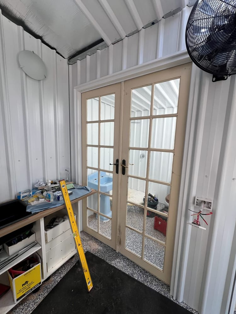 The french doors part way through installation, with tools and a level on the bench