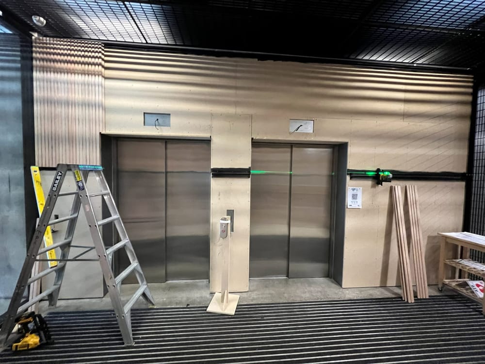 Timber-look panelling installed around lift doors in a commercial lobby